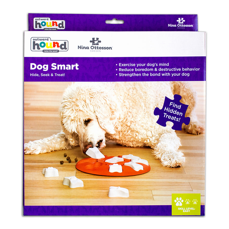 Outward Hound Nina Ottosson Dog Smart Level 1 puzzle toy packaging showing a fluffy white dog nosing the orange puzzle board to find hidden treats