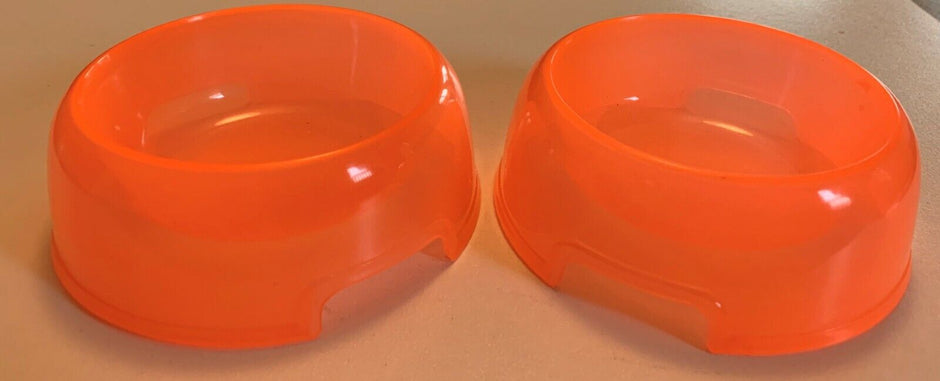 Two bright orange round plastic dog bowls from Lessmar, shown side by side on a neutral surface.