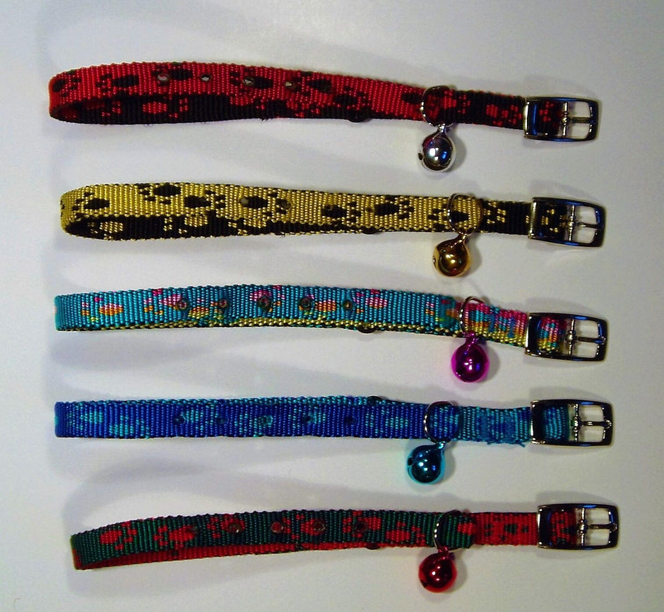 Five paw print cat collars laid flat, showing all available colour variants — red/black, black/yellow, multicolour, blue, and red/green — each with a metal buckle and coloured bell.