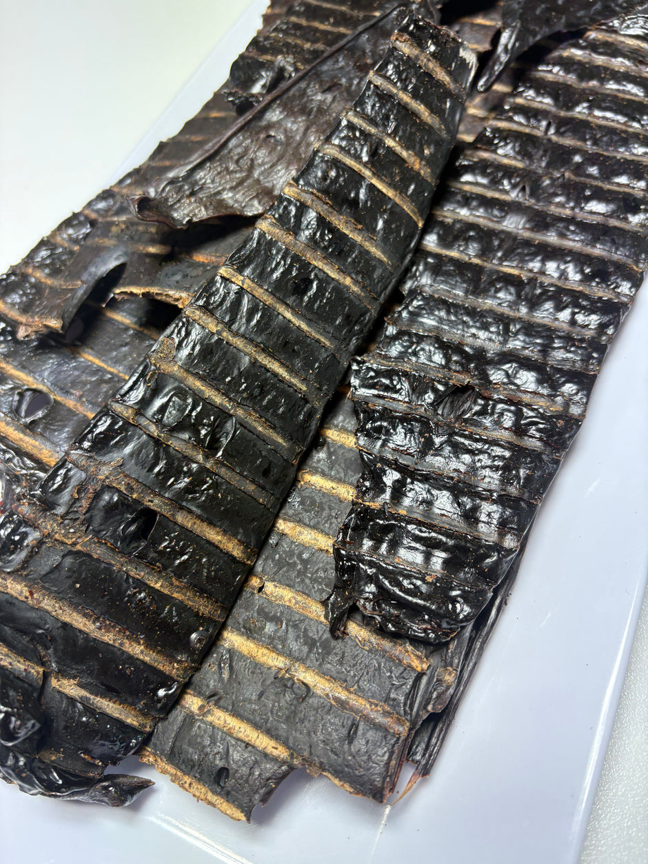 Close-up of scored dried beef liver dog treats stacked on a white surface, showing dark brown colour and textured surface