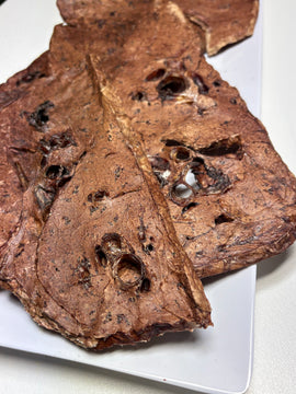 Close-up of two large dried Australian beef lung crisp pieces showing their light, porous texture on a white plate
