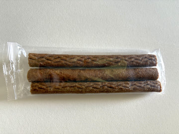 Three brown textured chicken sticks sealed in a clear plastic pack, viewed from above