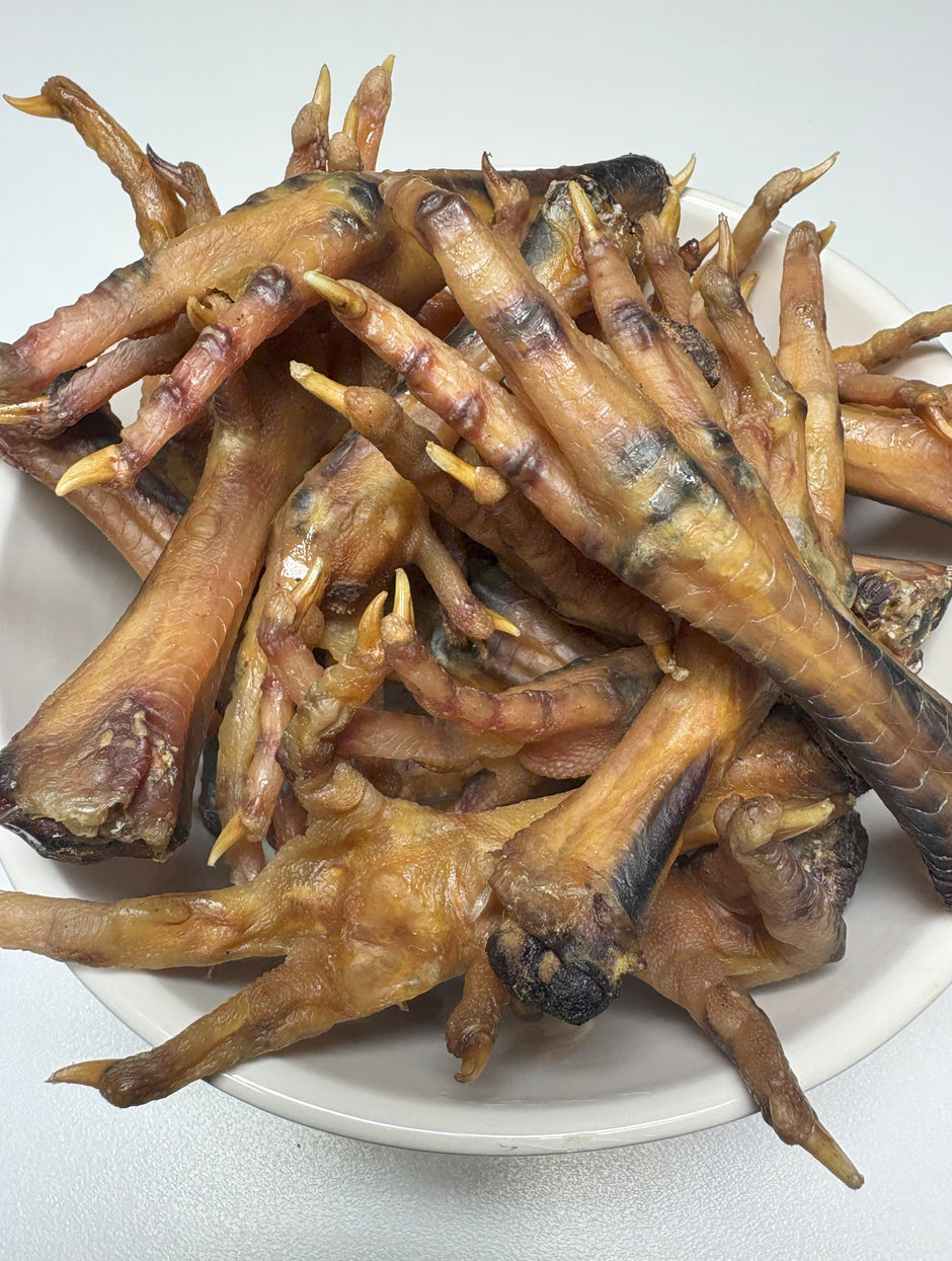 Dried Australian chicken feet piled on a white plate, showing the natural golden-brown colour of the treats