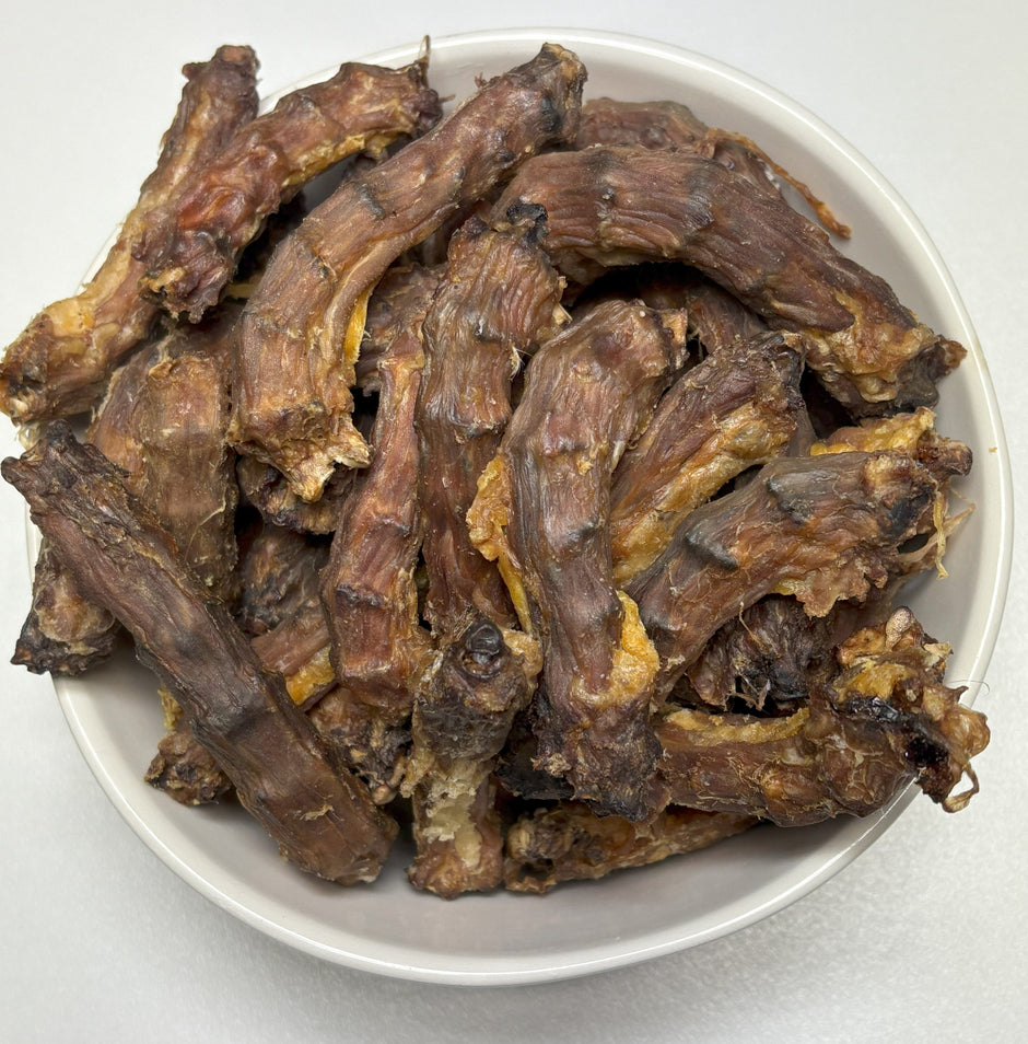 Dried Australian chicken necks piled in a white bowl, overhead view
