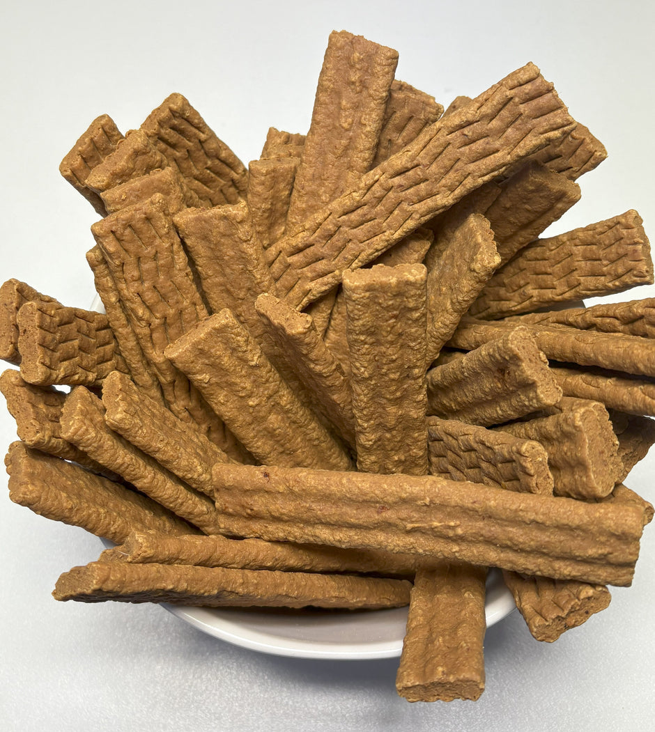 Overhead view of a white plate piled high with GoPetPlace chicken strap dog treats, showing their golden-brown colour and textured surface.