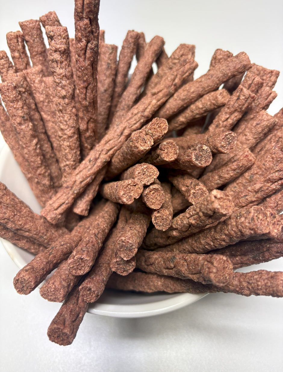 Overhead view of a white bowl filled with GoPetPlace kangaroo mini sticks dog treats