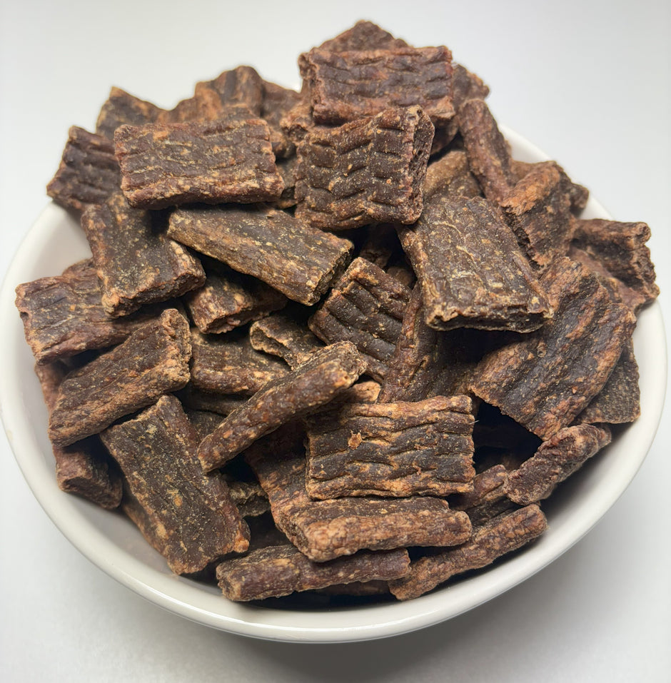 A white bowl filled with GoPetPlace kangaroo BBQ crinkle chips for dogs, viewed from above