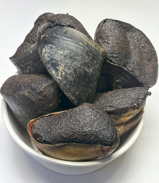 Ten kangaroo-filled cow hooves piled in a white bowl, showing their dark, textured outer surface and hollow interior