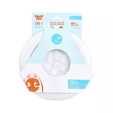 West Paw Zisc Glow in the Dark flying disc dog toy shown in its retail packaging, front view with paw-print detail visible through the centre hole