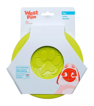 West Paw Zisc flying fetch dog disc in Granny Smith green, shown in retail packaging with Zogoflex branding and paw-print detail visible through the packaging window.