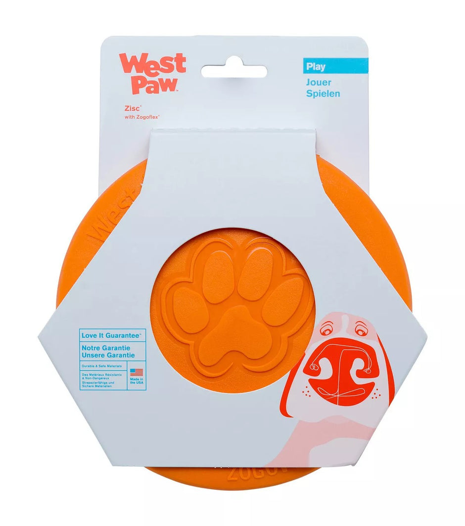 West Paw Zisc flying fetch dog toy in tangerine orange, shown in retail packaging with paw print detail on the disc face