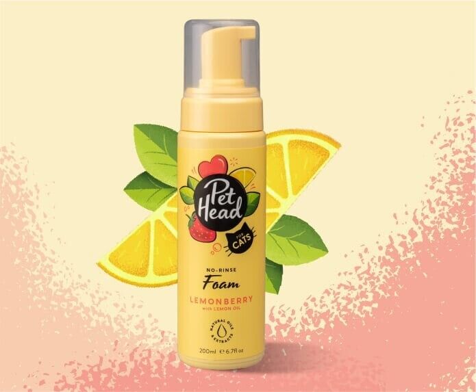 Pet Head Felin' Good Lemonberry No Rinse Foam for cats in a yellow pump bottle, surrounded by lemon slices and green leaves on a light yellow background.