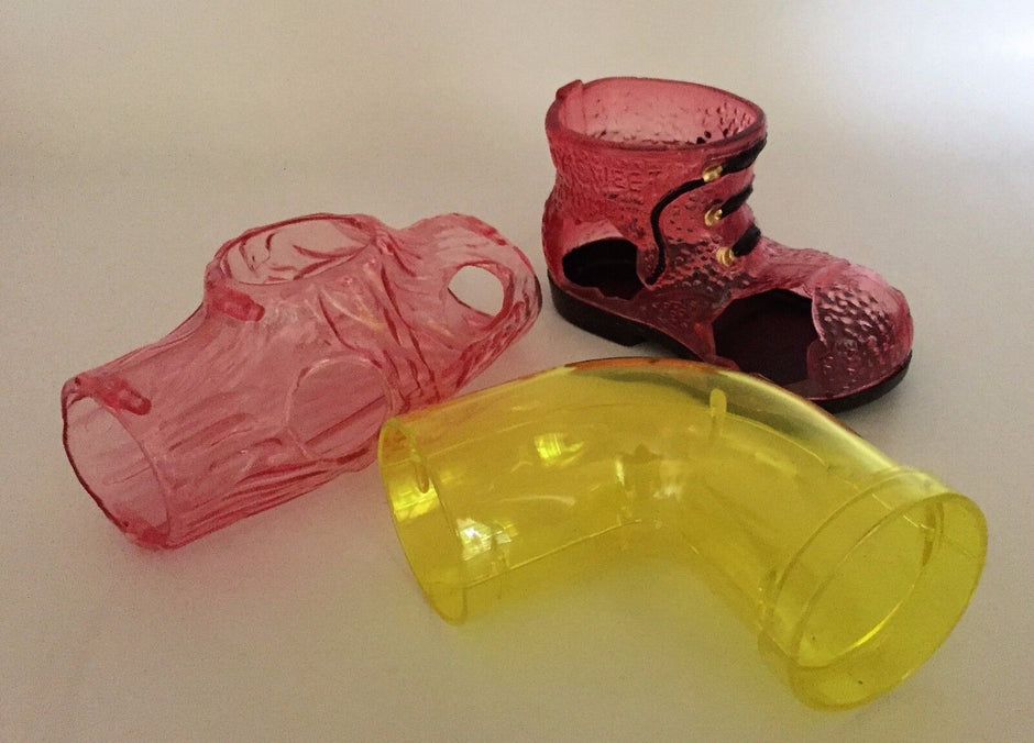 All three pieces of the Unipet play set laid out together — a pink translucent log, a pink translucent boot, and a yellow translucent curved pipe