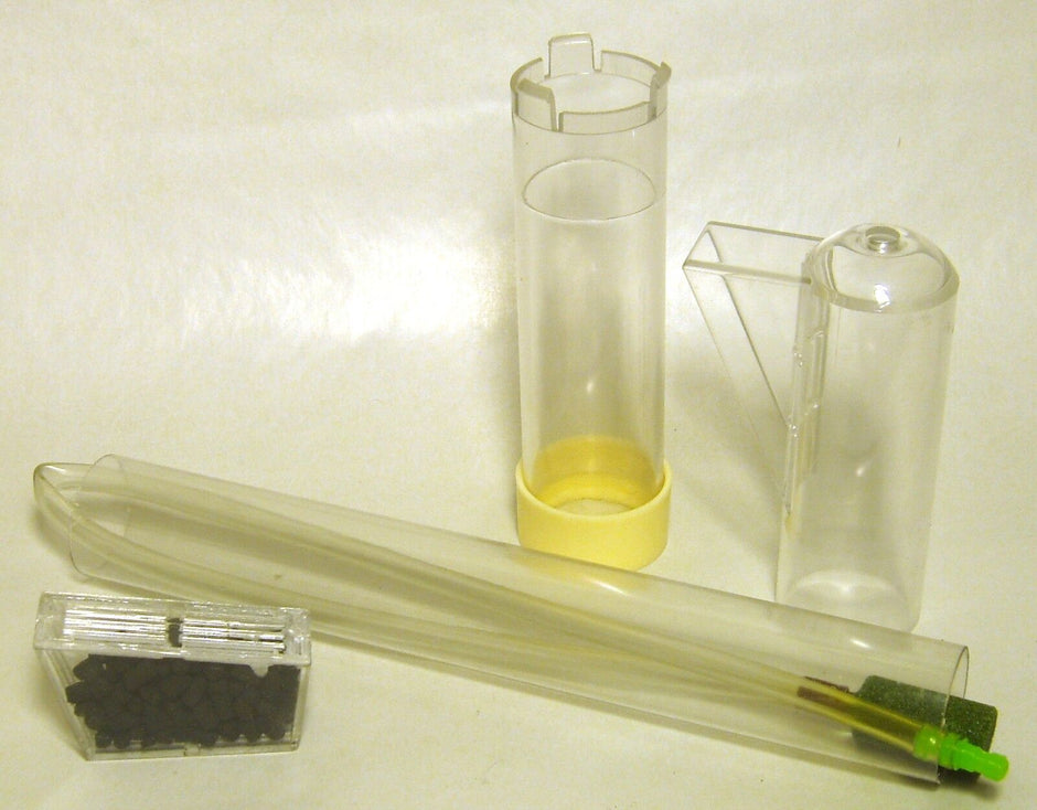 Components of the undergravel filter replacement uplift pack laid out flat: uplift tube with yellow base ring, exhaust fitting, airline tube with air stone, and disposable carbon cartridge in a plastic case.