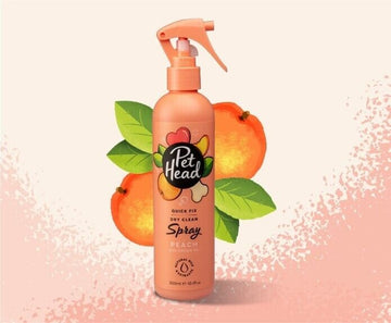 Pet Head Quick Fix Dry Clean Spray bottle in peach with trigger nozzle, shown against a peachy background with illustrated fruit and leaves