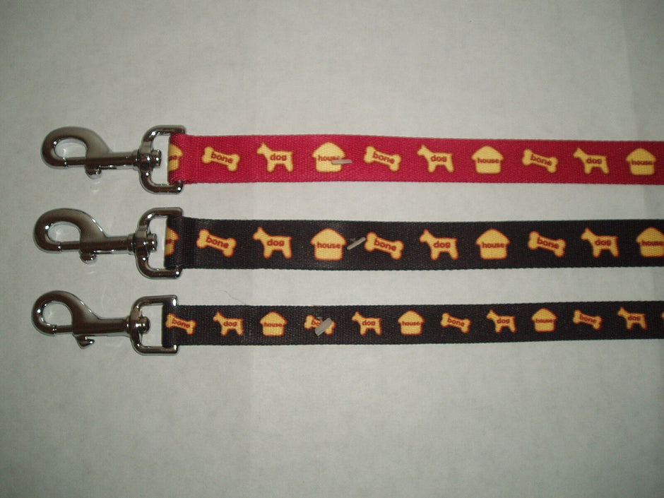 Three GoPetPlace nylon dog leads laid flat — one red and two dark brown — each 25mm wide with a repeating house, bone and dog motif and a silver clip fastener.