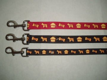 Three GoPetPlace nylon dog leads laid flat — one red and two dark brown — each 25mm wide with a repeating house, bone and dog motif and a silver clip fastener.