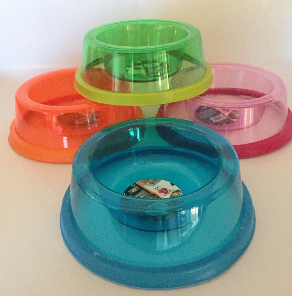 Four translucent acrylic pet bowls in orange, green, pink, and blue arranged together, showing the wide non-slip base and shallow bowl shape.