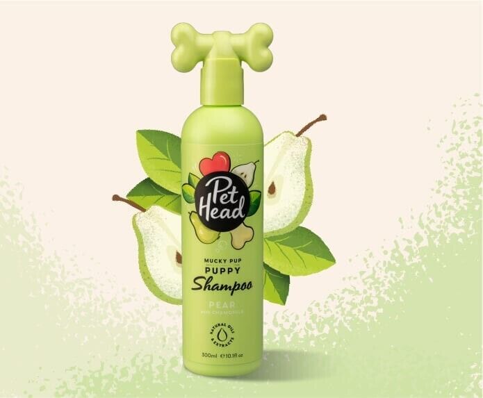 Pet Head Mucky Pup Puppy Shampoo 300ml bottle in lime green with a bone-shaped pump cap, surrounded by illustrated pear and leaf graphics.
